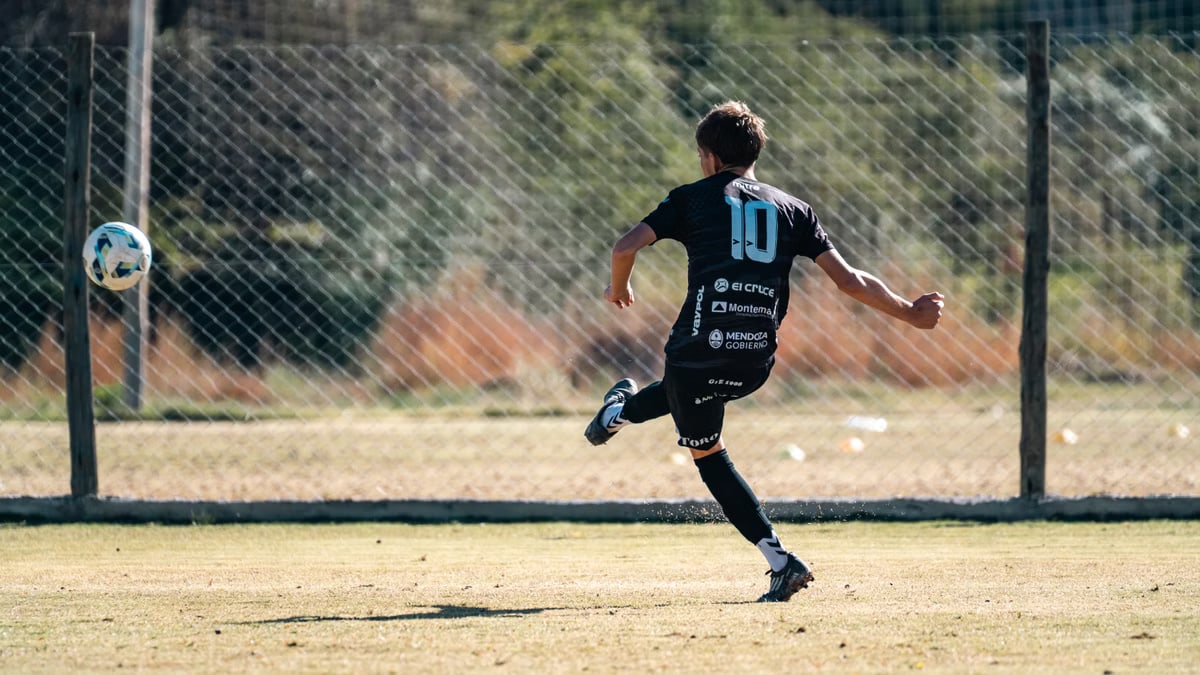 Youth soccer player in motion kicking a ball on a sunny outdoor field.